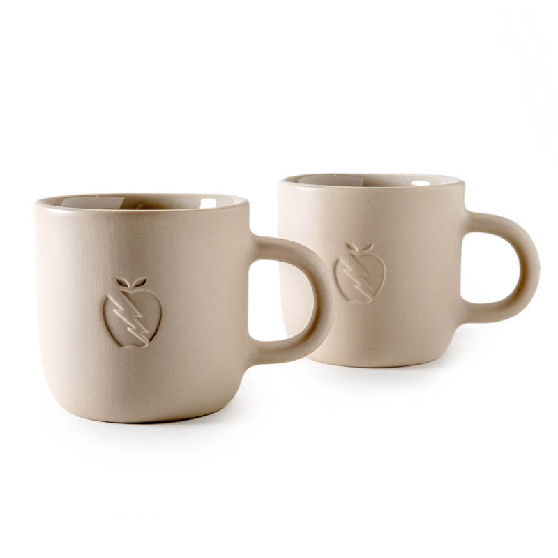 Pair of Great Jones x Franca cream colored ceramic mugs on white background