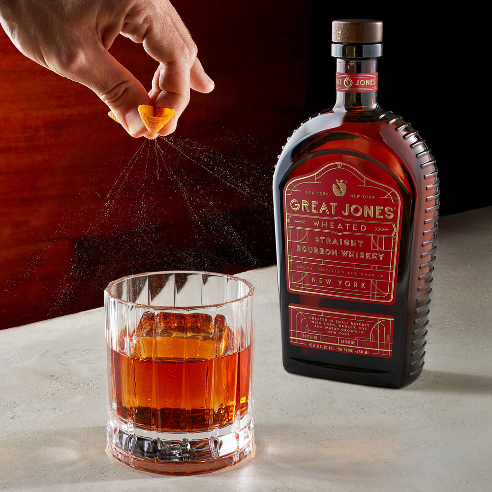 Great Jones Wheated Bourbon next to a neat pour of whiskey in a cocktail glass