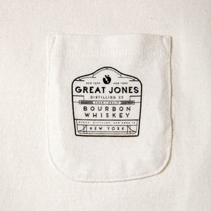 
                  
                    Closeup of Great Jones bottle label illustration on pocket tee
                  
                