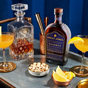 
                  
                    Great Jones Straight Bourbon and Cocktail, Lemon Wedges and Pistachio on Blue Background
                  
                